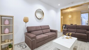 Ein modernes Wohnzimmer mit einem braunen Sofa, einem weißen Couchtisch und einem Holzregal mit Dekorationselementen.