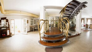 A spacious living area with a central spiral staircase, a dining area with chairs, and a kitchen visible in the background. - Köstem Hotel (Cesme)