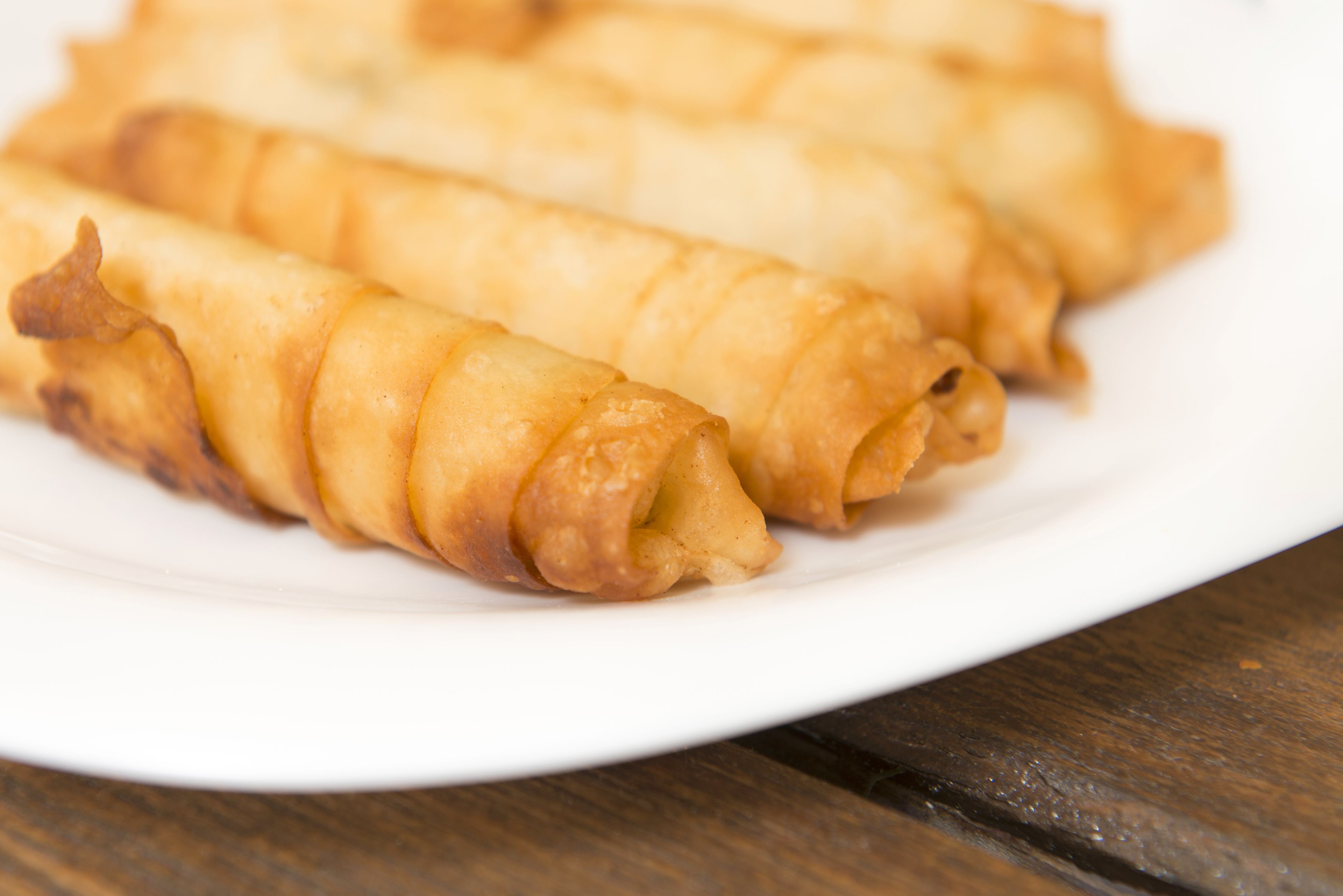 A plate of golden-brown fried rolls on a white plate.