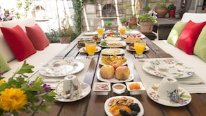 A breakfast table set with plates of food, drinks, and a floral tablecloth. - Köstem Hotel (Cesme)