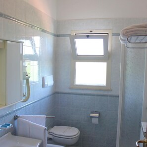 A bathroom with a toilet, a sink, a mirror, and a window. - Hotel Acquario (Vasto)