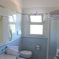 Un bagno con il water, un lavandino, uno specchio e una finestra.