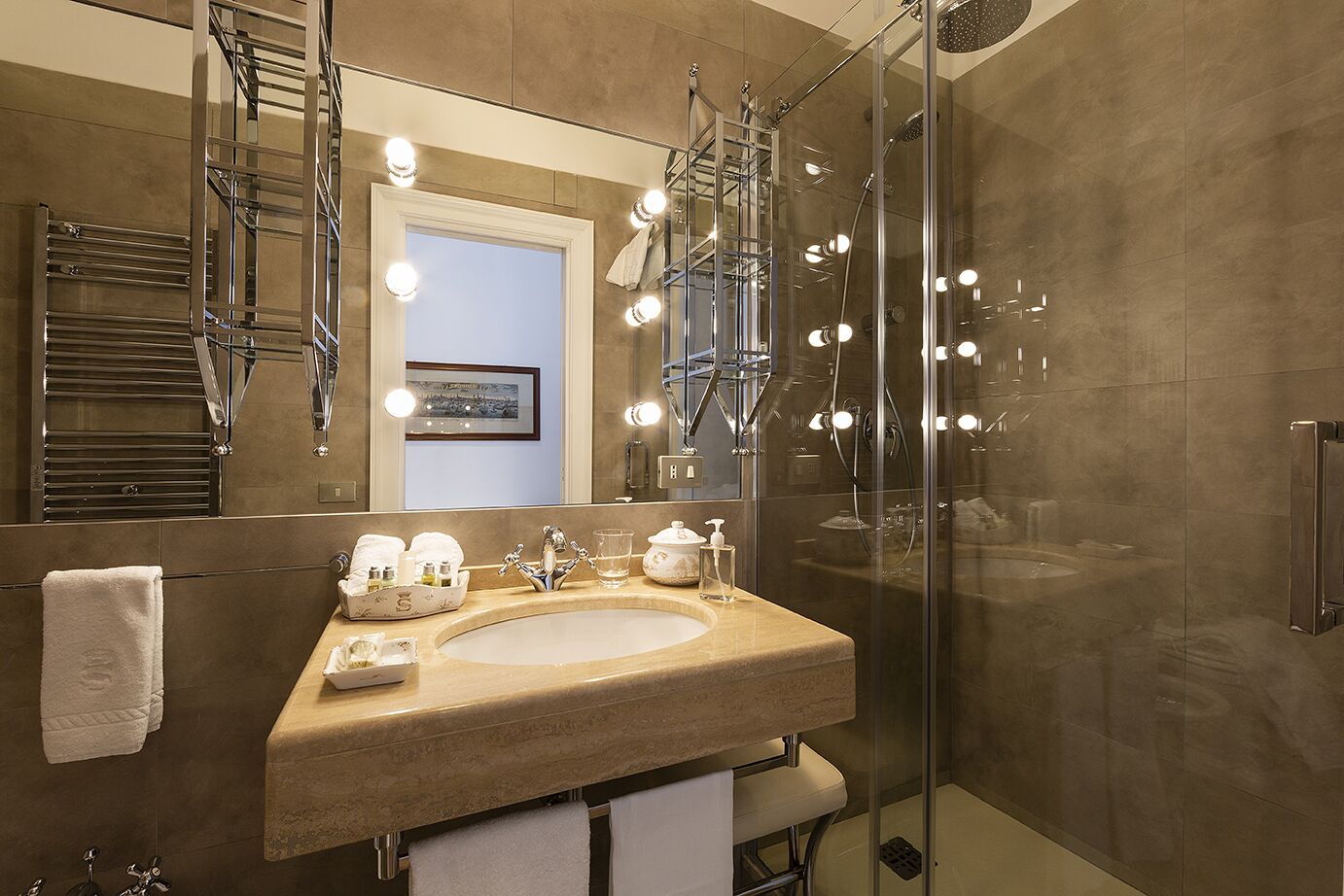A modern bathroom with a large mirror, a sink, and a glass-enclosed shower.