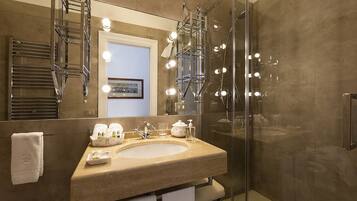 A modern bathroom with a large mirror, a sink, and a glass-enclosed shower.