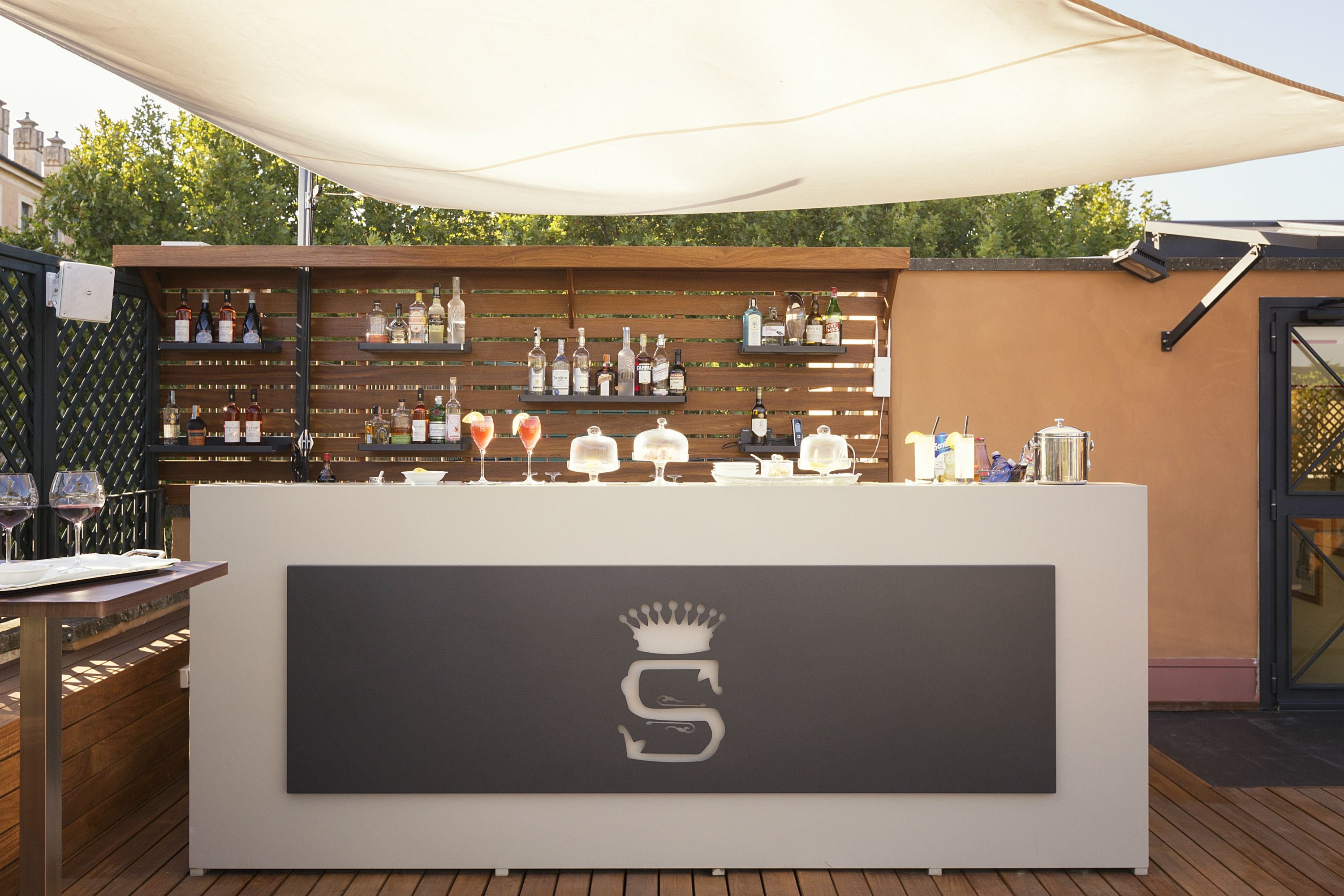 A bar area with a white counter, shelves of liquor bottles, and a canopy overhead.