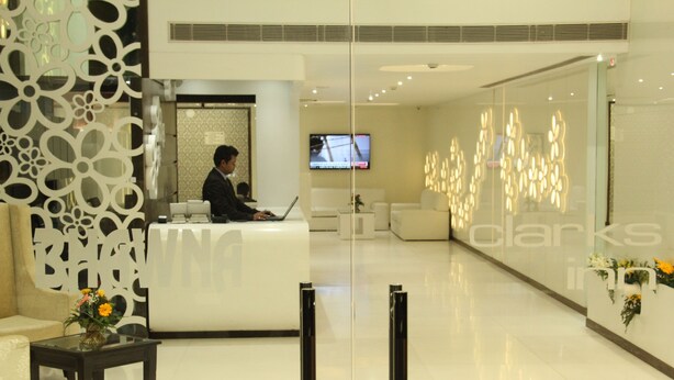 Uma área de recepção moderna com balcão de atendimento, televisão e painel decorativo.