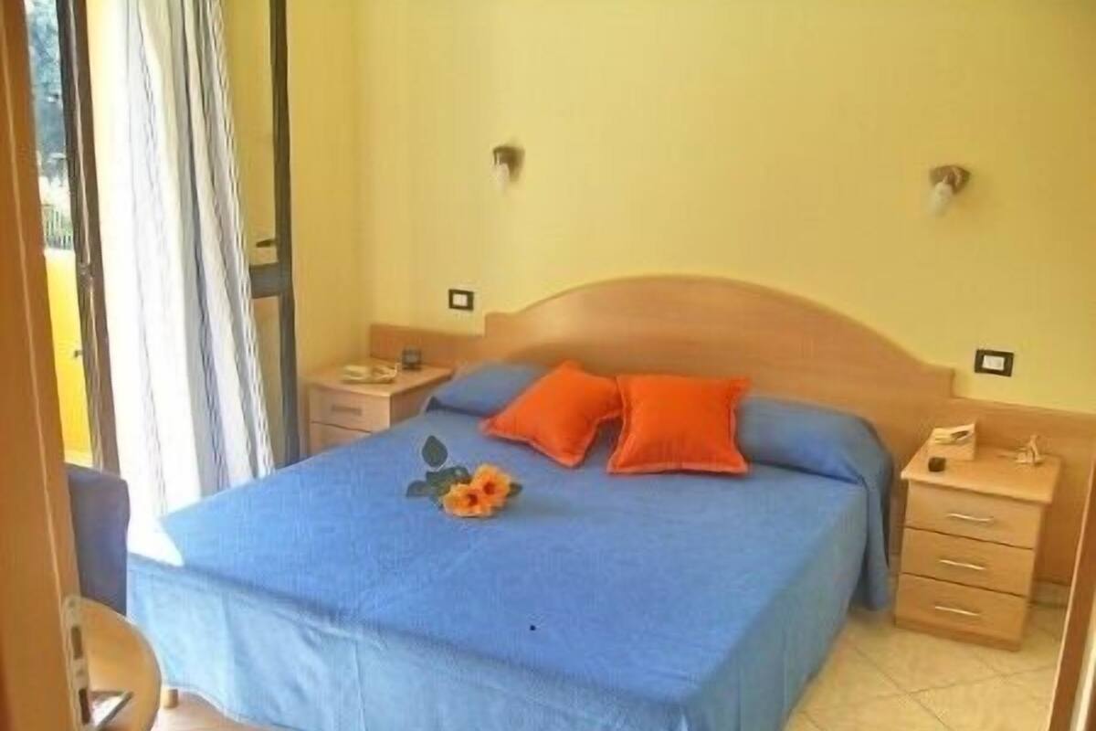 A bedroom with a single bed, two nightstands, and a window with curtains.