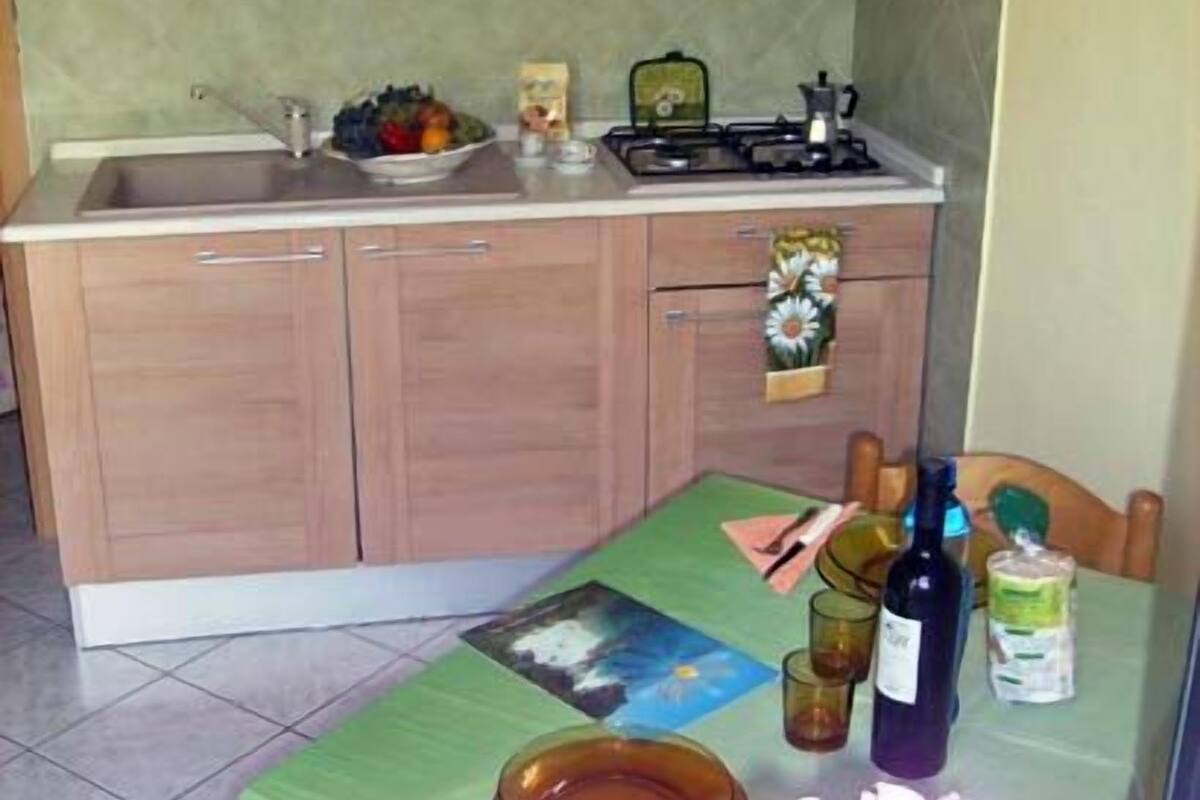 A kitchen with wooden cabinets, a sink, a stove, and a dining table with a placemat.