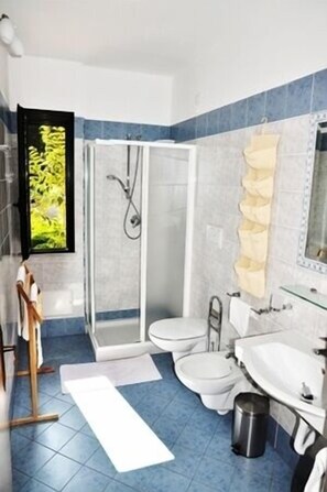 A bathroom with a shower, two toilets, a sink, and a mirror. - Residence Hotel Riviera Calabra (Zambrone)