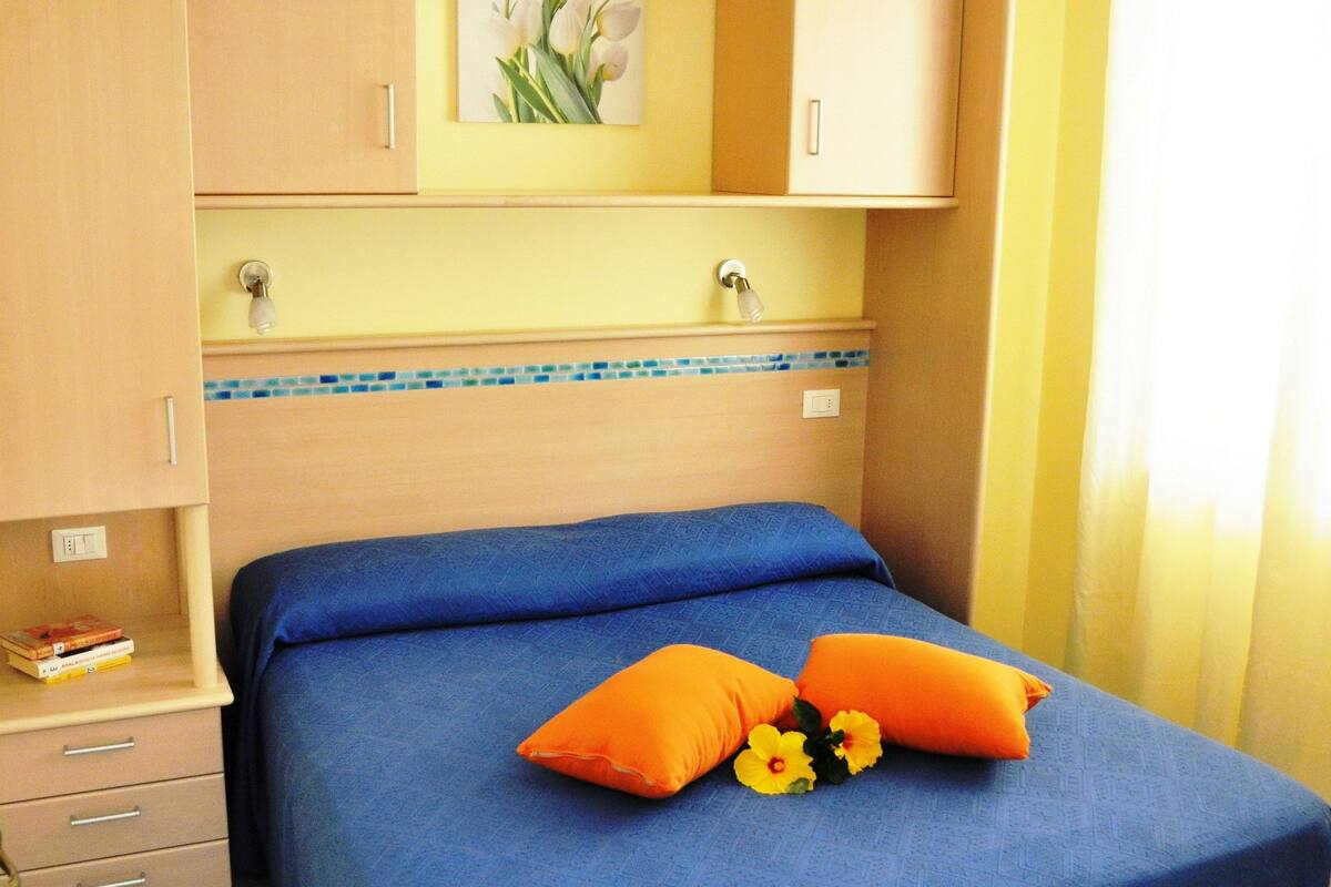 A bedroom with a bed, a nightstand, a wardrobe, and a painting on the wall.