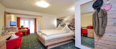 Una habitación de hotel con una cama, un escritorio, una silla, un espejo y un perchero.