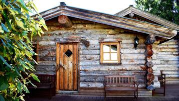 A rustic log cabin with a wooden door, a window, and a bench outside.