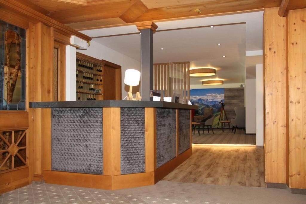A reception area with a wooden reception desk, a seating area with a view, and a wall with a painting.