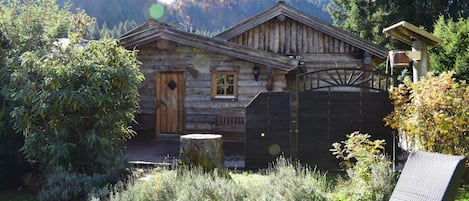 Une cabane rustique en rondins de bois, avec une porte en bois, une petite fenêtre et une clôture en bois.