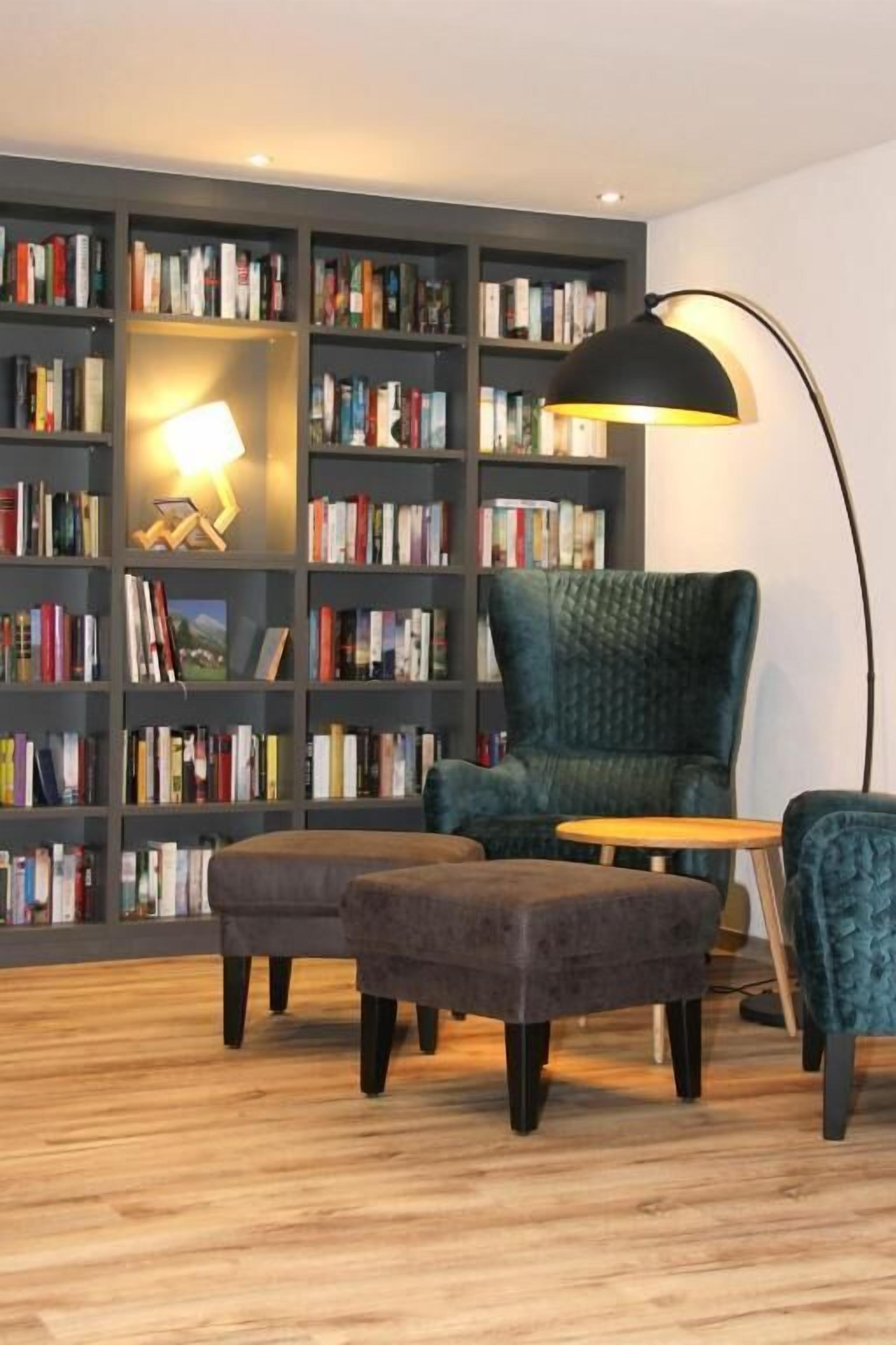 A room with a bookshelf, a chair, and a lamp.