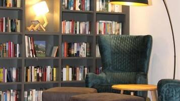A room with a bookshelf, a chair, and a lamp.