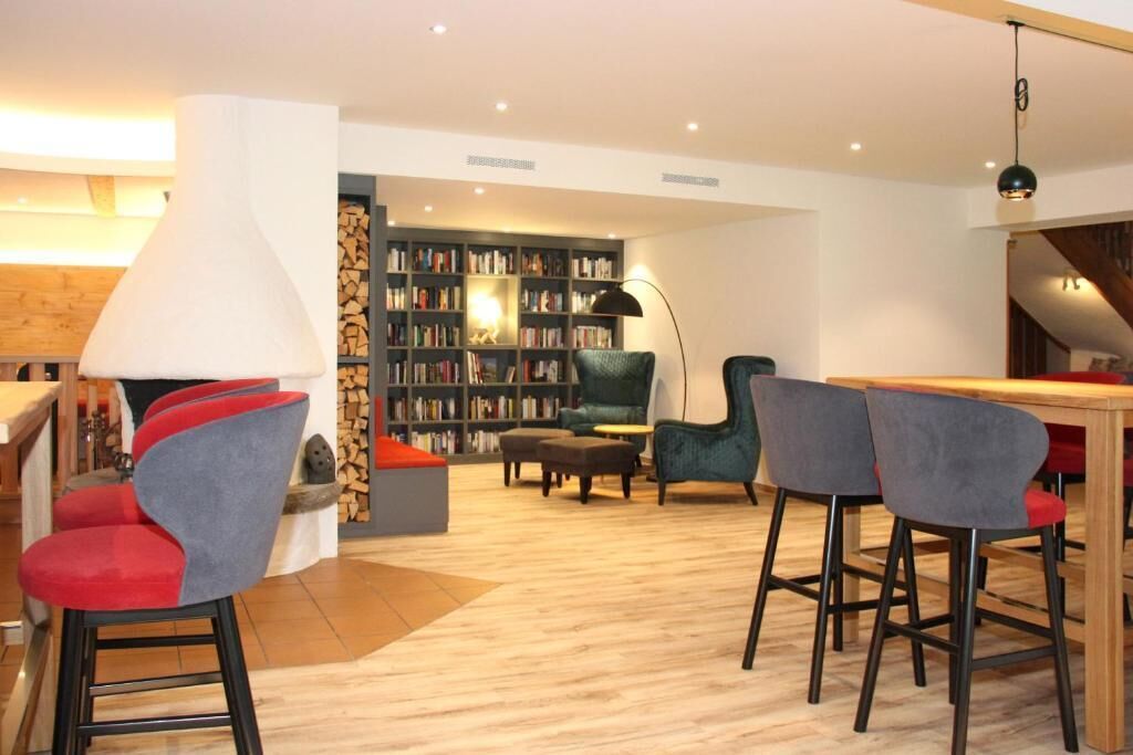 Ein modernes Wohnzimmer mit Bücherregal, einer Essecke mit Barhocker und einem Kamin.