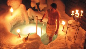 A person in a snow-filled room with a bathtub, candles, and a candelabra. - Sonnenbichl Hotel am Rotfischbach (Fischen im Allgaeu)
