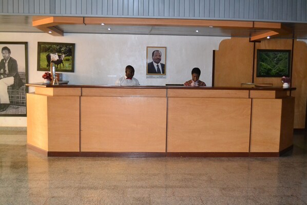A reception desk with three staff members, framed pictures on the wall, and a wooden counter.