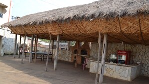 A covered outdoor seating area with a stone wall and a Coca-Cola vending machine. - Mawa Hotel (Bamenda)