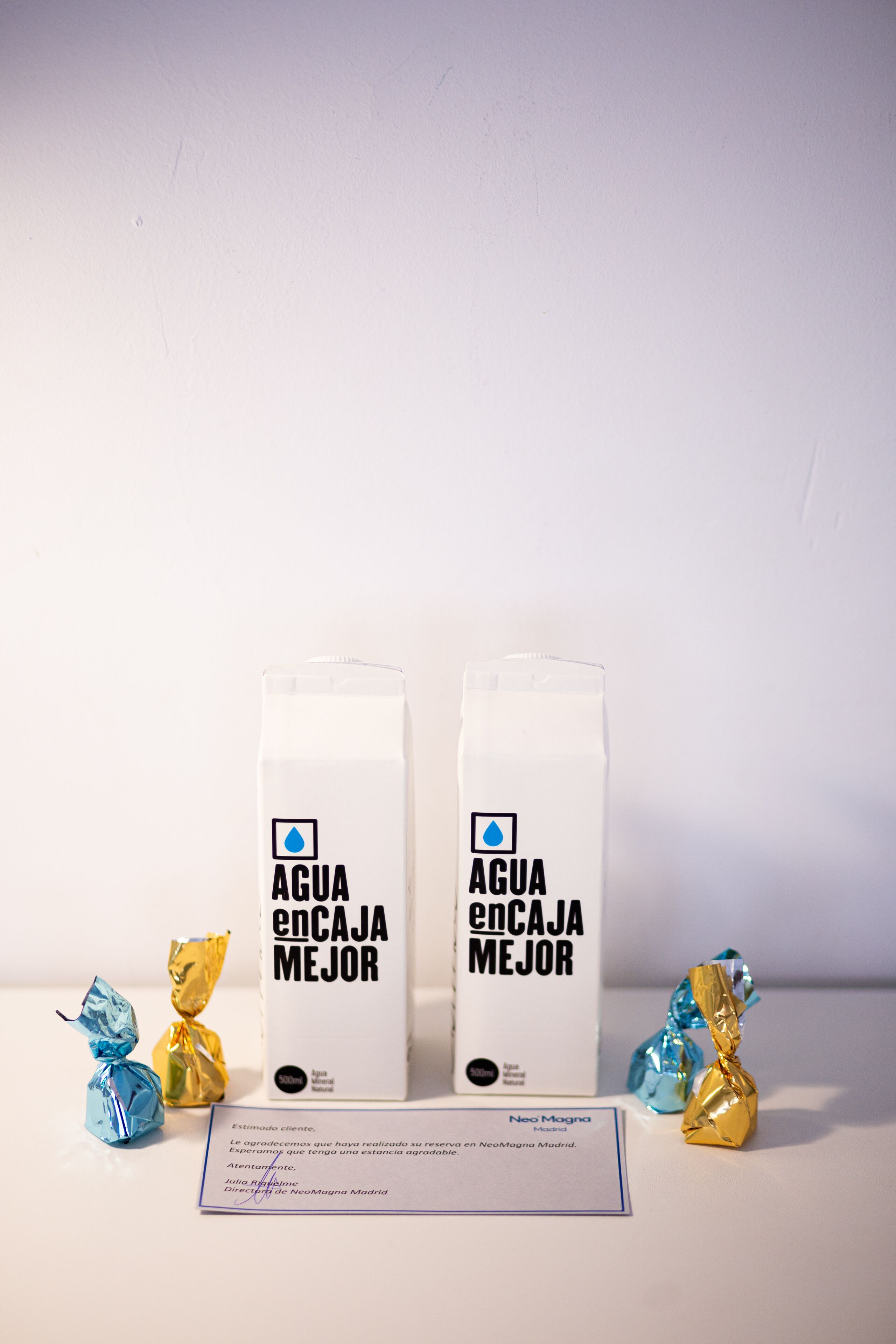 To kartoner mælk med teksten ”AGUA ENCAJA MEJOR” og to chokolader indpakket i folie.