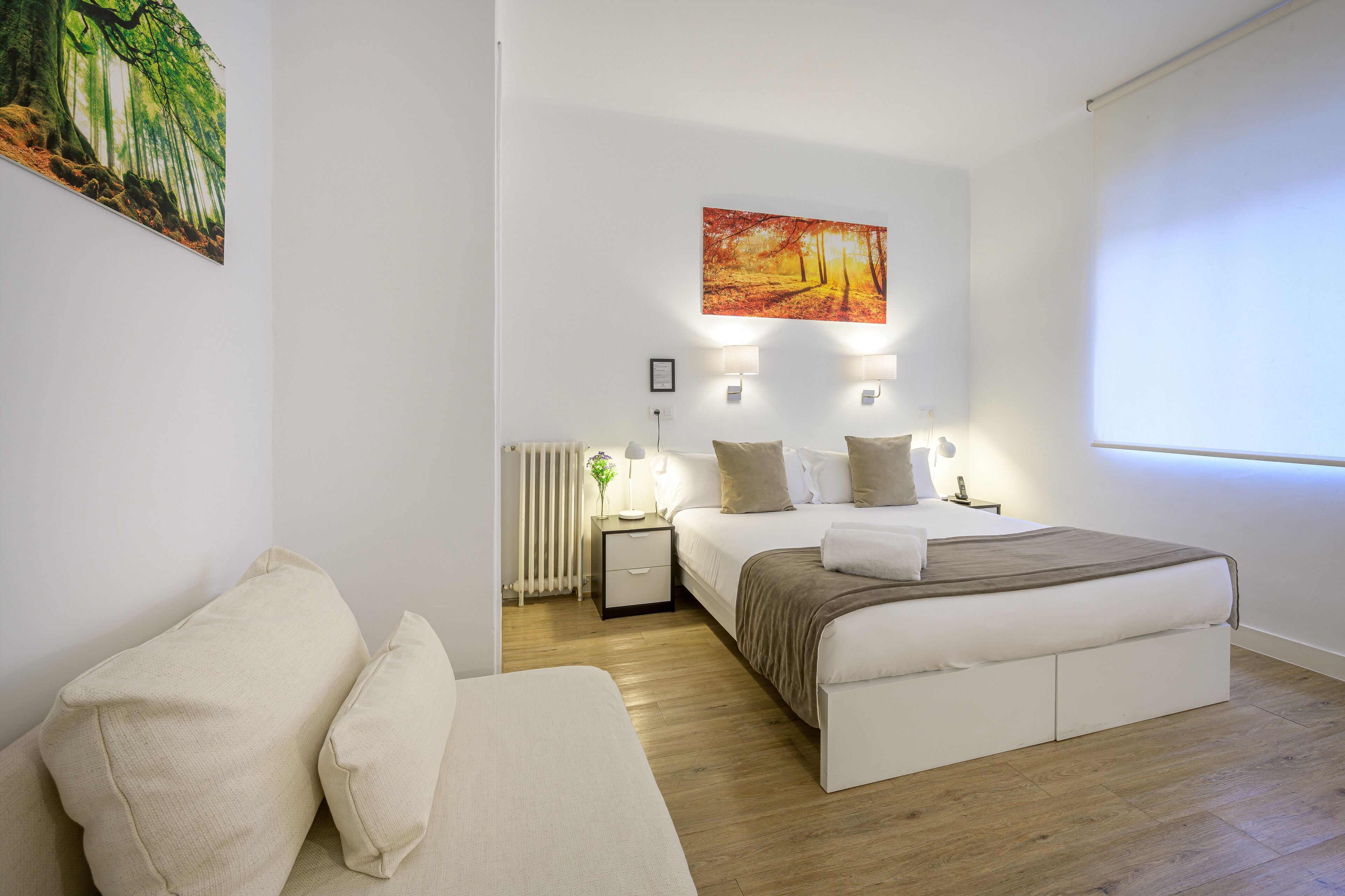 A modern bedroom with a large bed, bedside tables, and a wall-mounted painting.