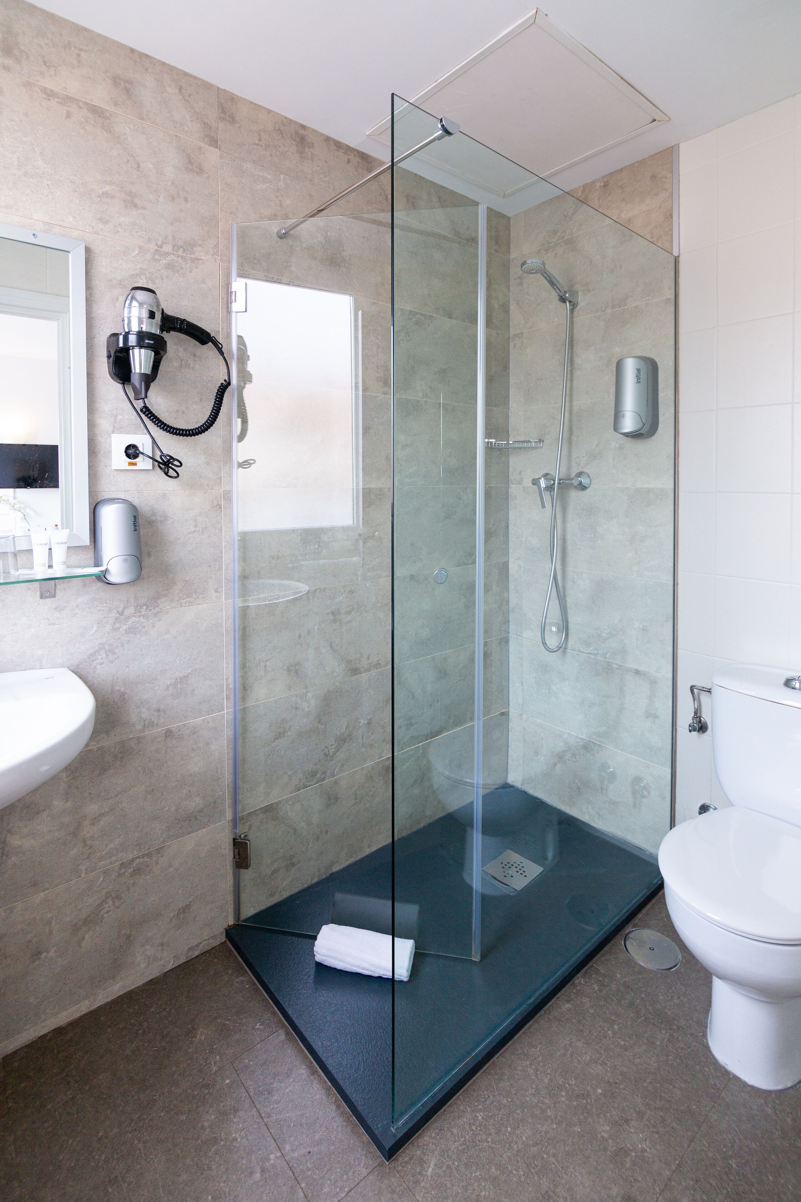 Een moderne badkamer met een douchecabine van glas, een witte wastafel en een toilet.
