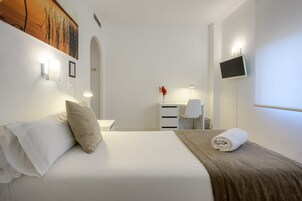 Ein Hotelzimmer mit Bett, Schreibtisch, Stuhl, Fernseher und einem Bild an der Wand.