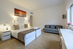 Ein modernes Hotelzimmer mit einem Bett, einer Couch, einem Schreibtisch und einem Fernseher.
