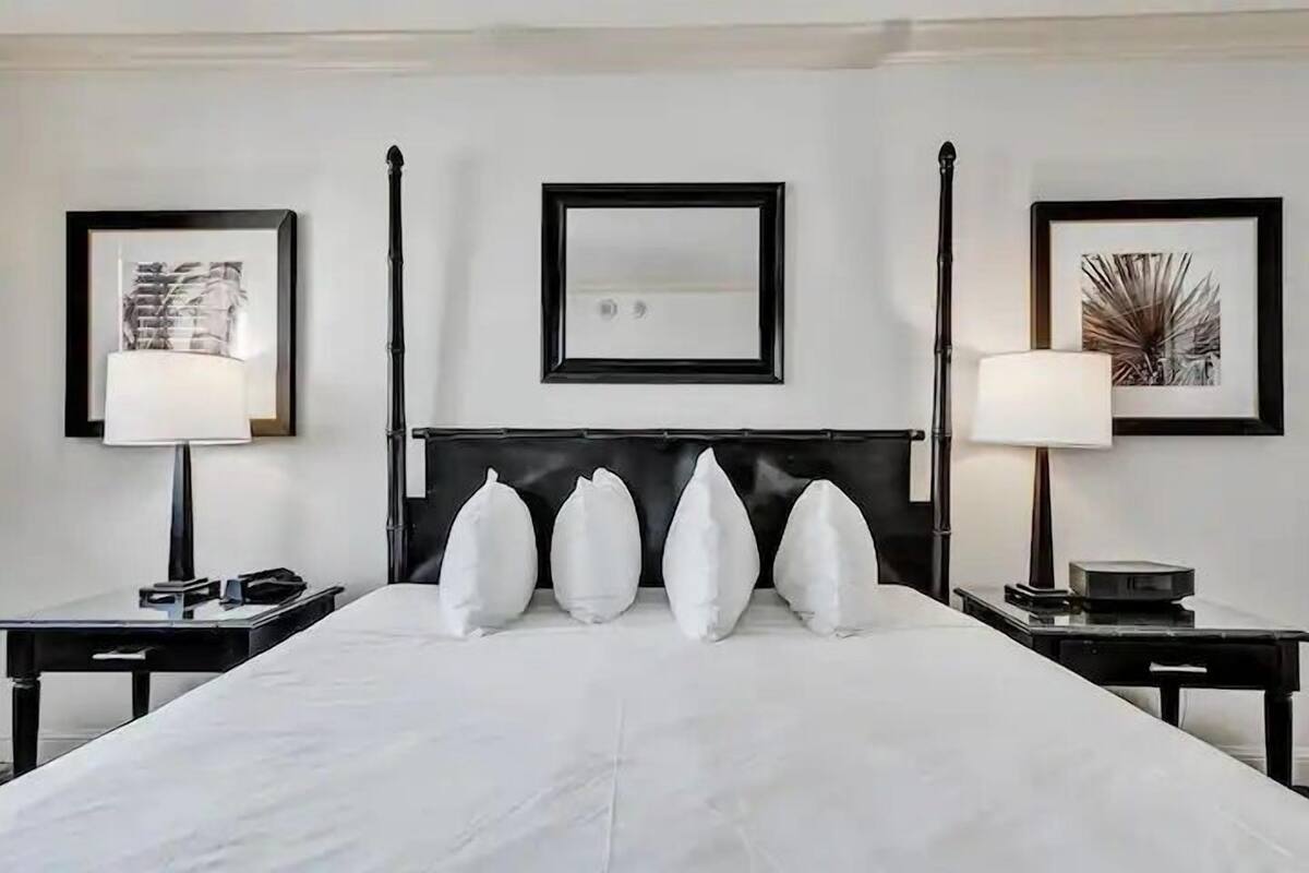 A hotel room with a large bed, two bedside tables, a headboard, and framed artwork on the walls.