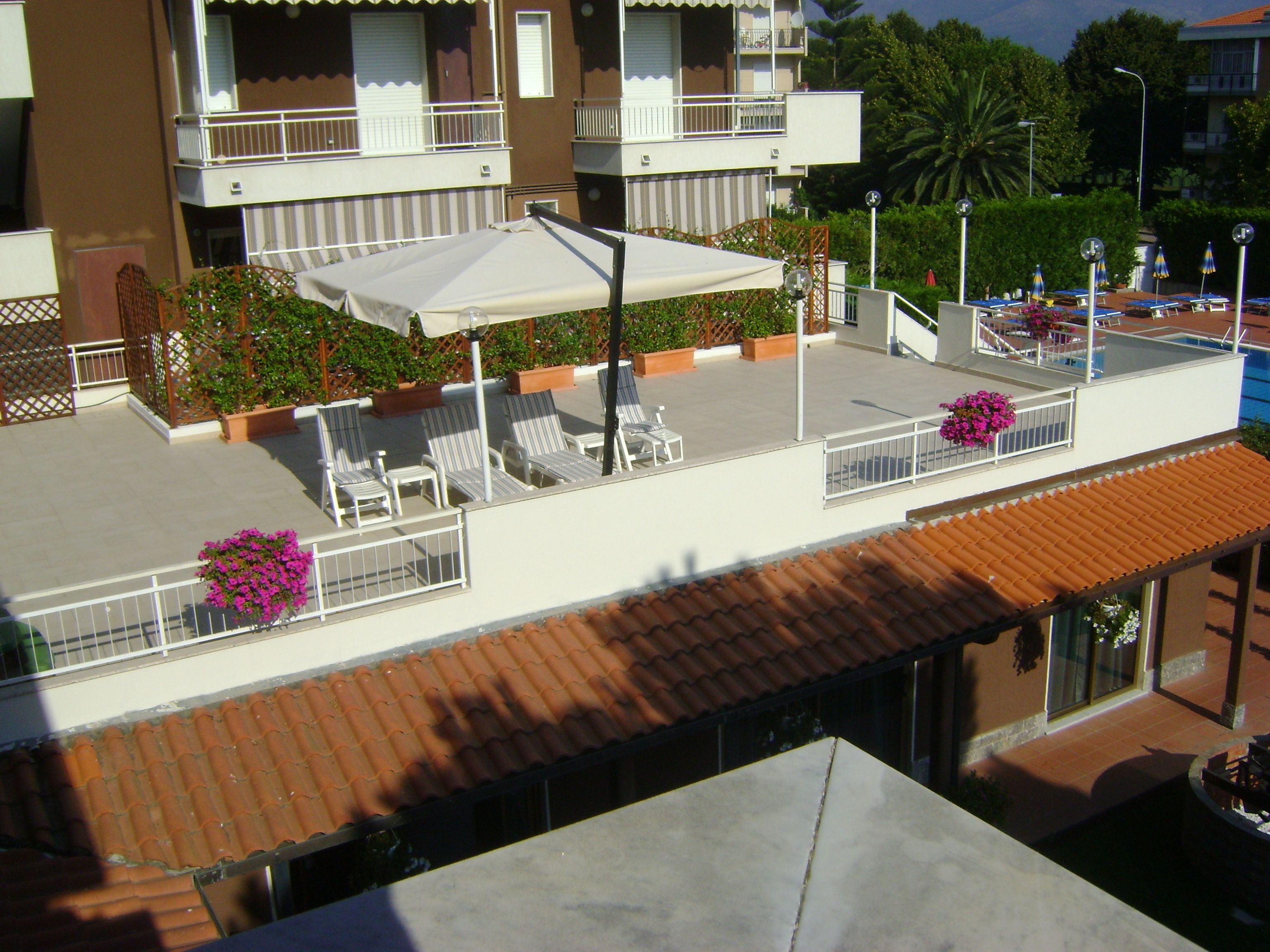 A rooftop terrace with outdoor seating, a pool, and a view of the surrounding buildings.
