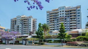 Um edifício moderno com vários varandas e um jardim bem cuidado.