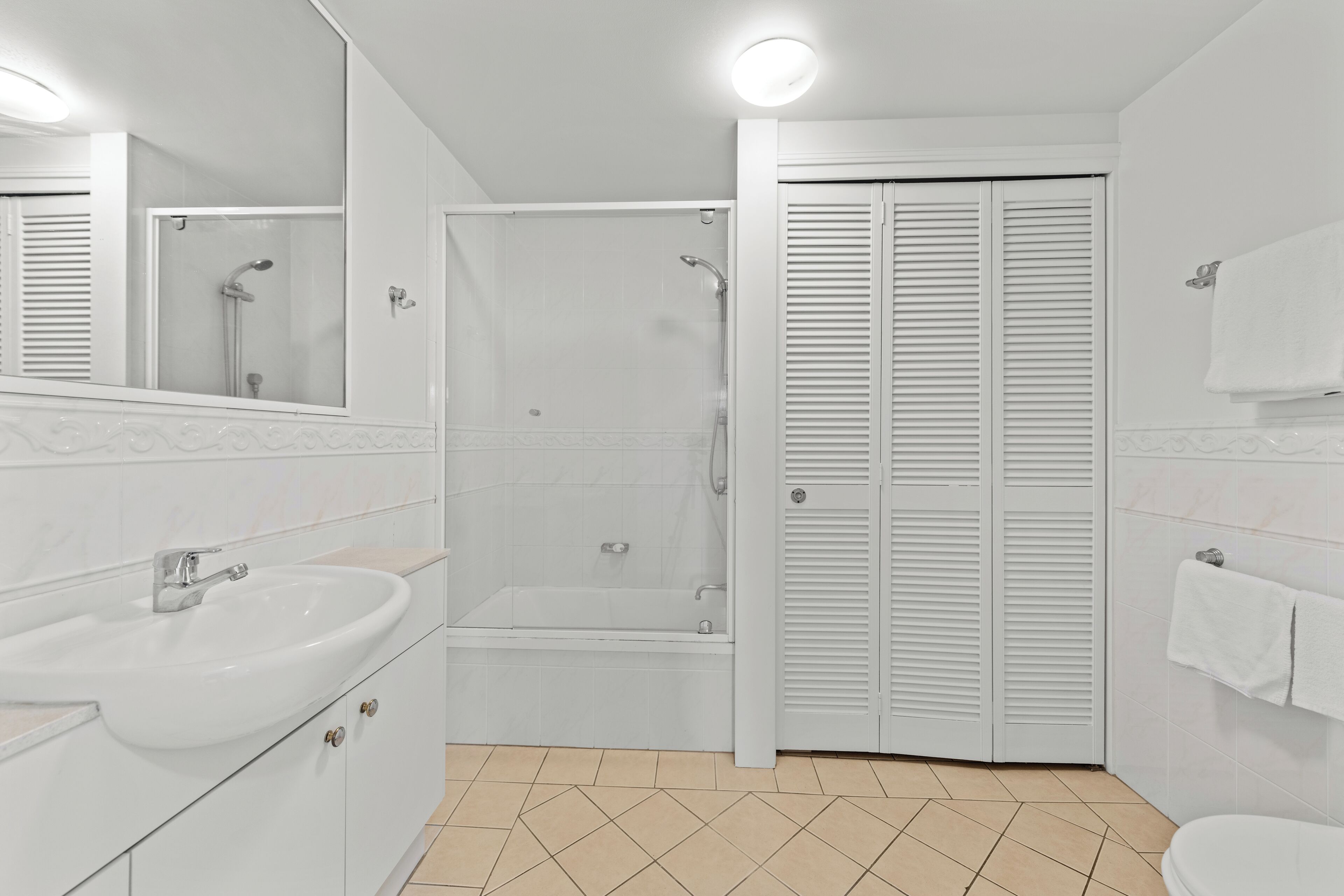 Une salle de bain équipée d’un lavabo, d’un miroir, d’une douche et de toilettes.