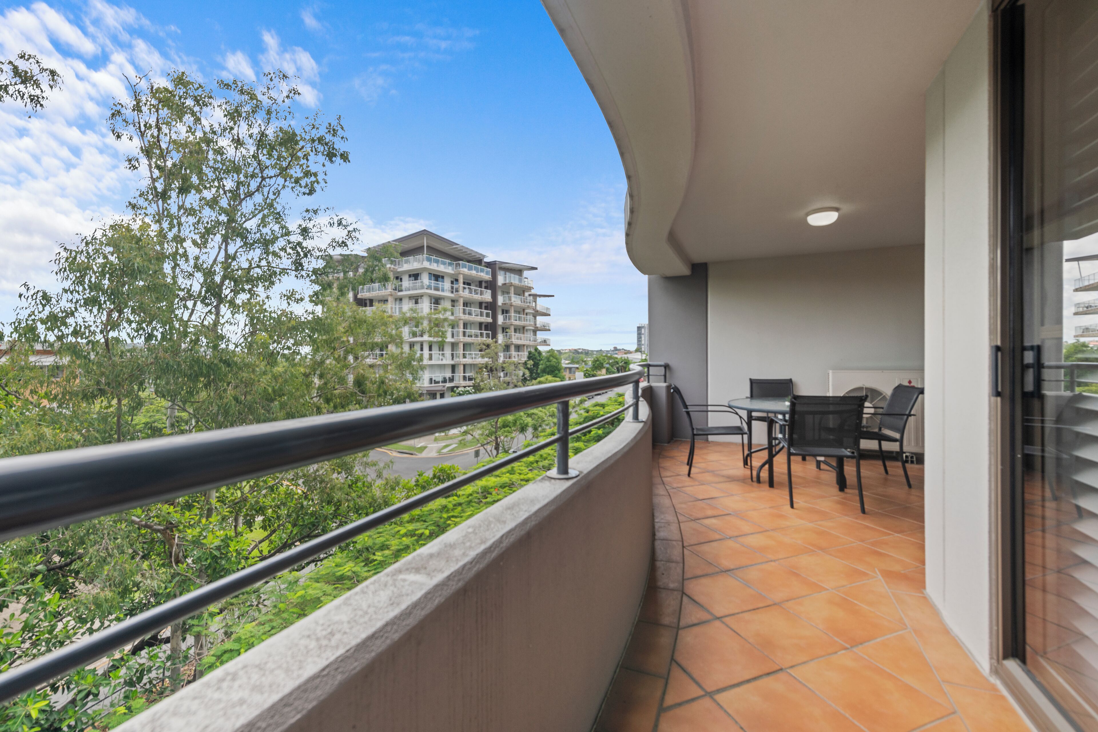 A balcony with a view of a building and trees.
