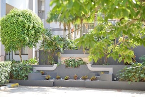 A landscaped outdoor area with a variety of plants, a large tree, and a modern architectural structure with steps.