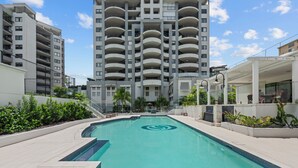 Um edifício moderno com várias varandas e uma piscina em frente.