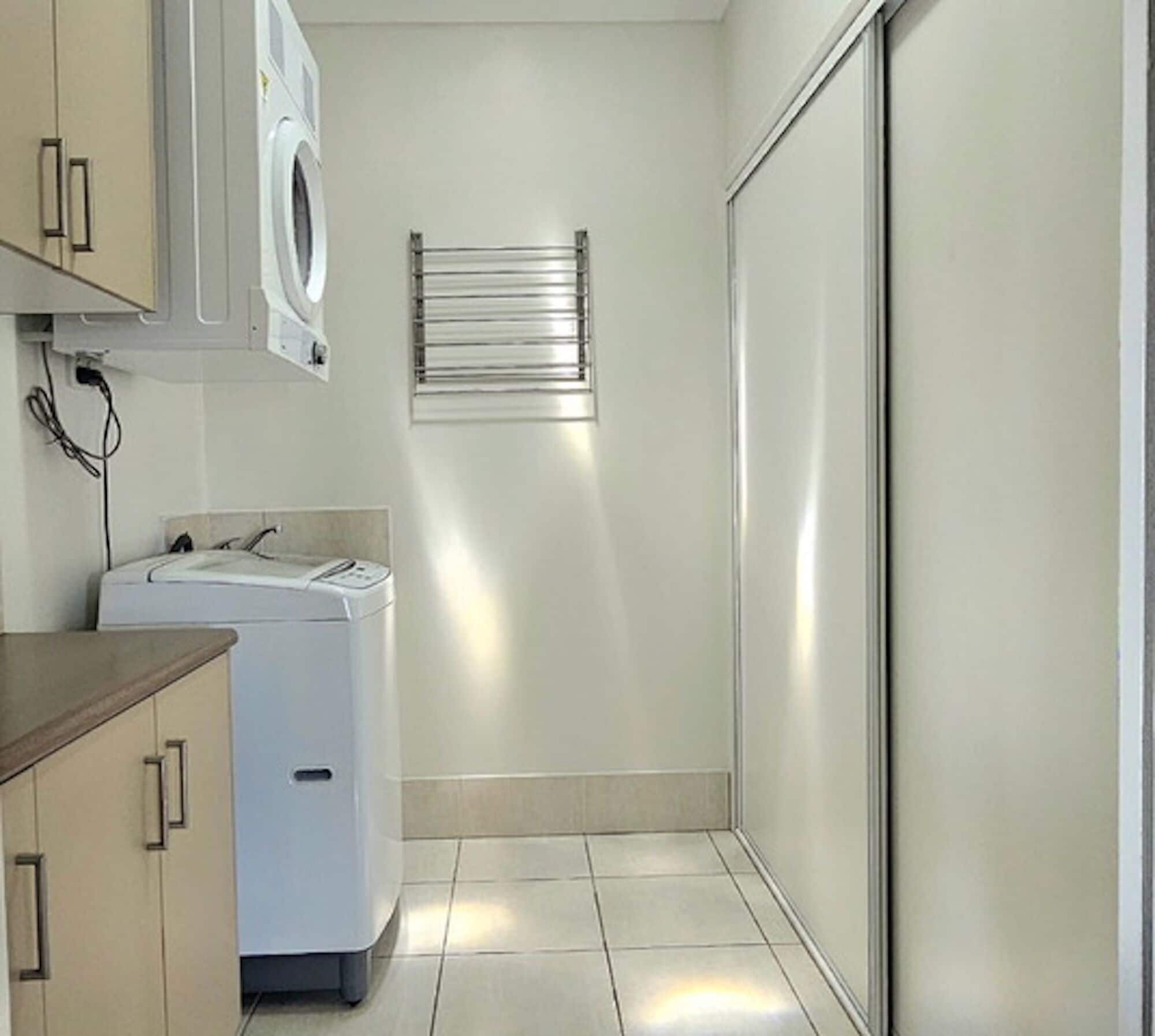 A laundry room with a washing machine, dryer, and a towel rack.