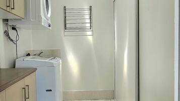 A laundry room with a washing machine, dryer, and a towel rack.