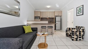 A modern living room with a grey sofa, a small wooden side table, and a black and white patterned sofa. - Emerald Inn by Travellers (Emerald)