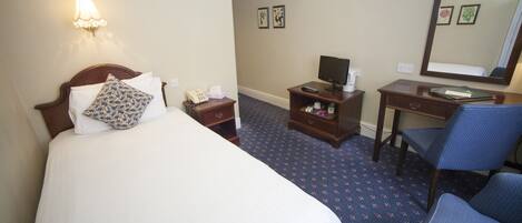 A hotel room with a bed, a desk, a chair, a telephone, and a mirror.