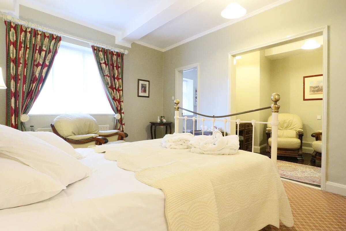 Habitación de hotel con una cama grande, una silla, un escritorio y un espejo.