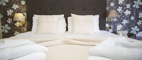 A neatly made bed with two pillows, a bedside lamp, and a telephone on the nightstand.