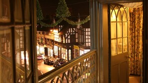 Une vue depuis une fenêtre donnant sur une rue la nuit, avec des bâtiments et des voitures.
