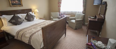 A hotel room with a large bed, a desk with a mirror, a chair, a television, and a painting on the wall.