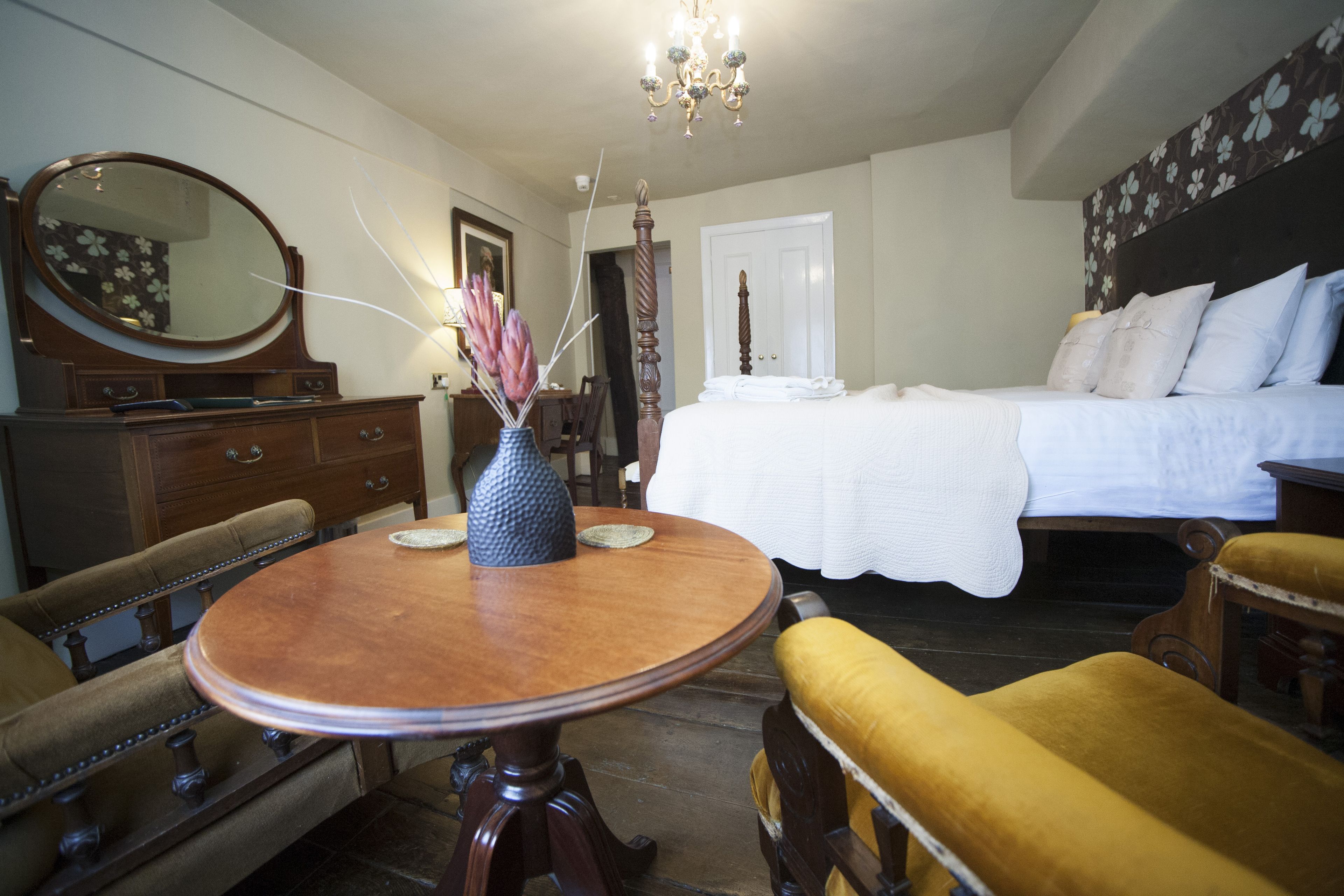 A bedroom with a bed, a dresser, a round wooden table, and a chair.