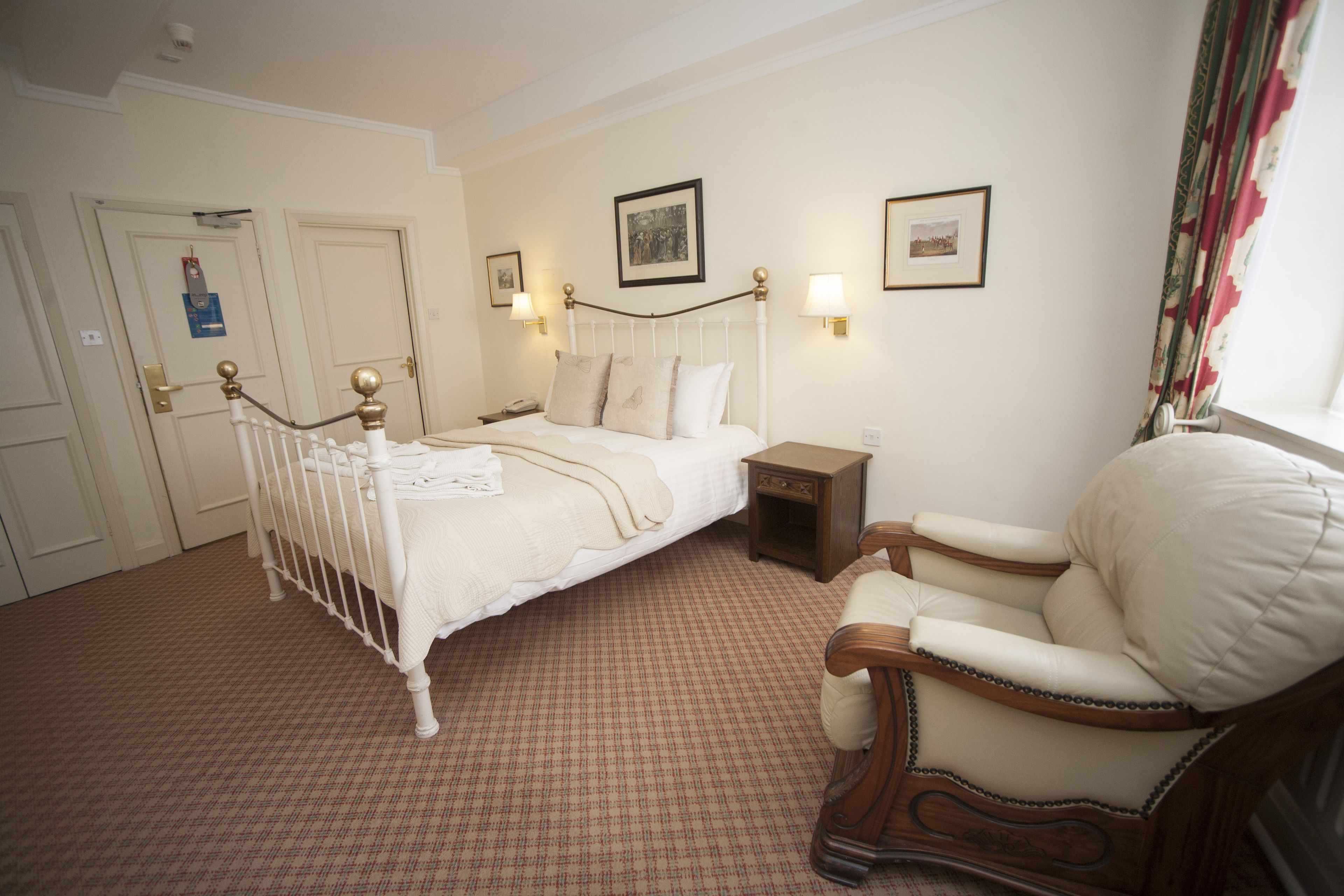 A bedroom with a bed, bedside table, chair, and two doors.