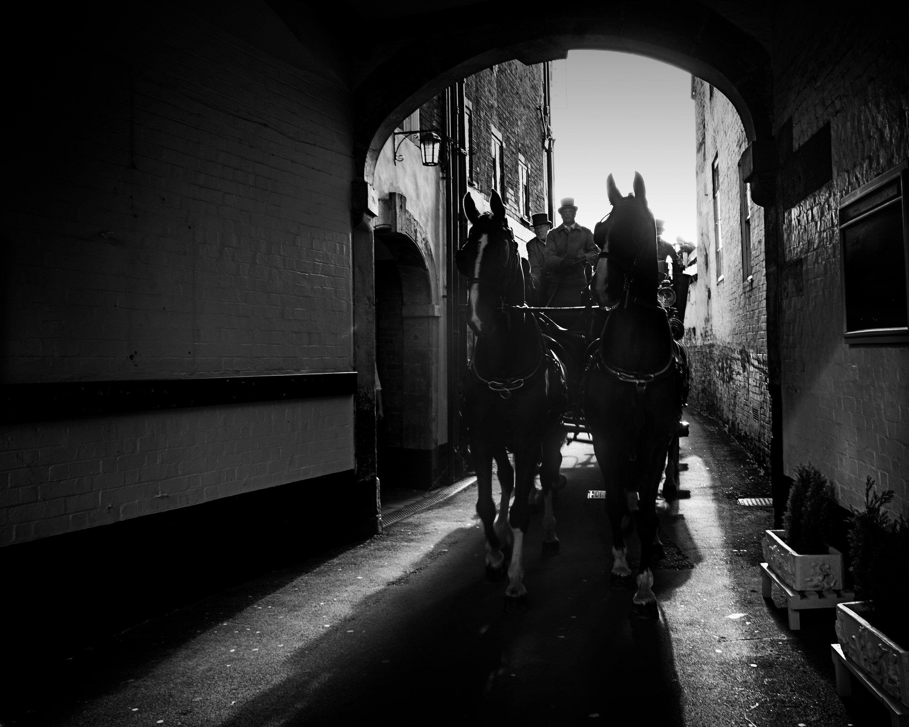 A narrow alleyway with brick walls and a horse-drawn carriage.