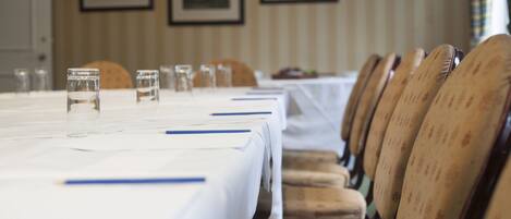 Un salón de conferencias con una larga mesa, sillas y vasos de agua.