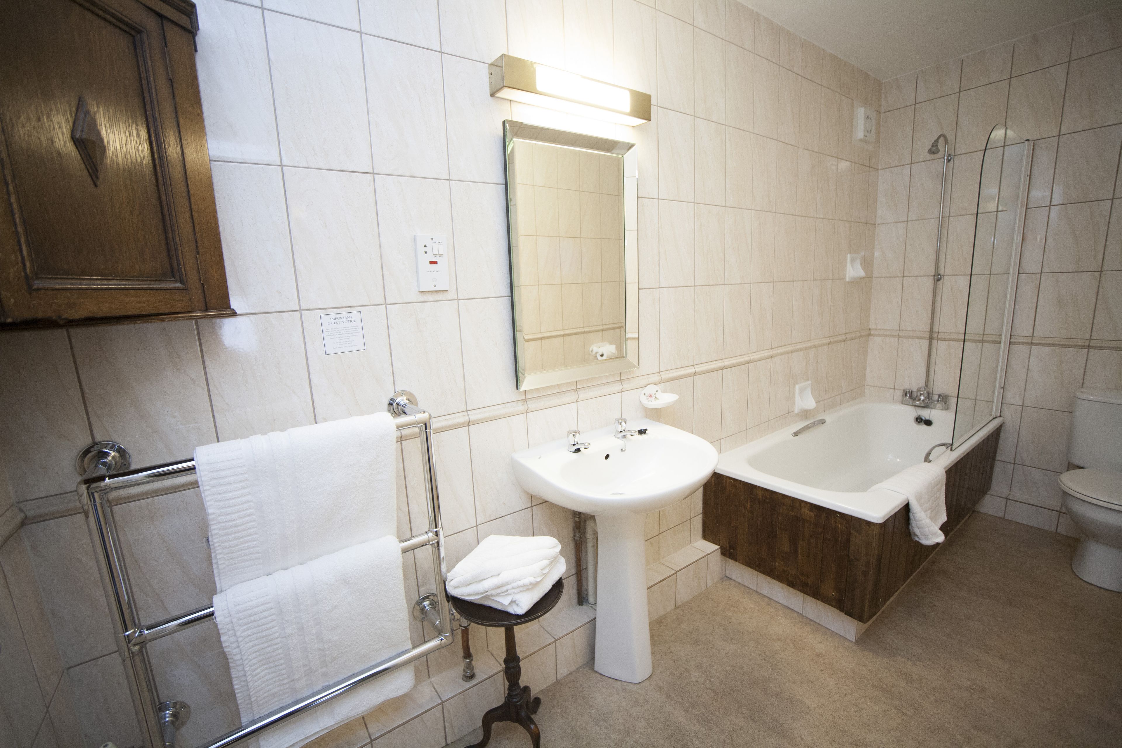 Une salle de bain avec un meuble-lavabo en bois, un lavabo sur colonne, une baignoire et des toilettes.