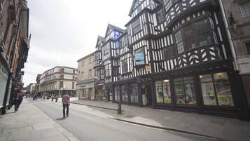 Una calle con edificios tradicionales de entramado de madera, cielo despejado y una acera para peatones.